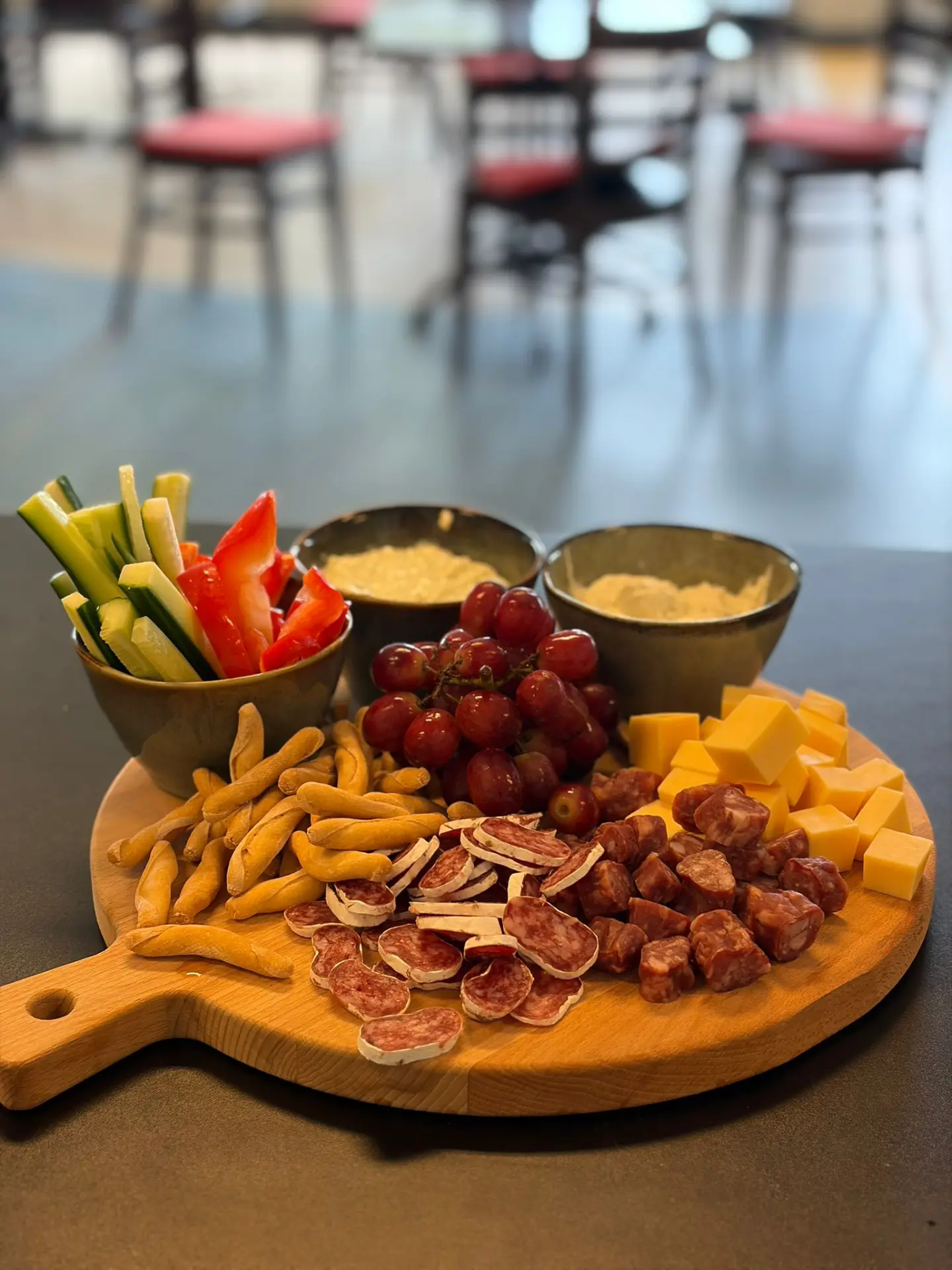 Rijkgevulde borrelplank met kaas, worst, groente, druiven en dips